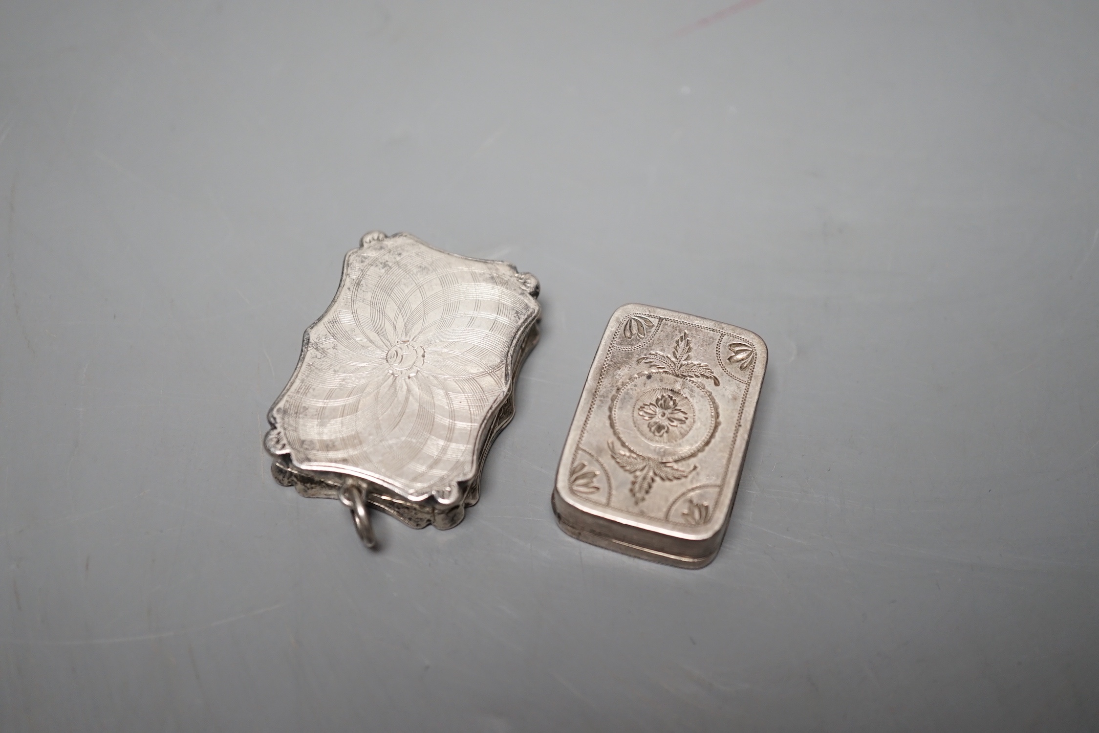 A Victorian engraved silver shaped rectangular vinaigrette, by Nathaniel Mills, Birmingham, 1845, 36mm and a George III silver vinaigrette, London, 1807, 31mm.